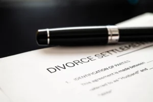 A close-up of a divorce settlement document with a black pen resting on top.