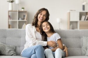 Young mother cuddling infant child in close portrait, both facing camera