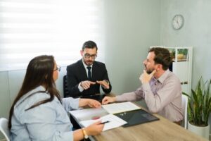 attorney in suit mediating discussion between couple across office desk with documents
